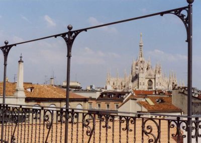 Parapetto in ferro battuto con motivi verticali e riccioli in palazzo Luxottica con vista sul duomo di Milano