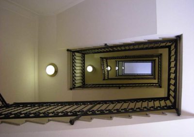 Scale in ferro battuto con motivi verticali e riccioli in palazzo Luxottica a Milano