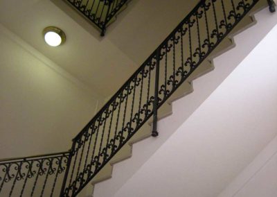 Scale in ferro battuto con motivi verticali e riccioli in palazzo Luxottica a Milano