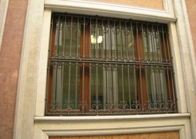 Inferriata in ferro battuto con motivi verticali e riccioli in palazzo Luxottica a Milano