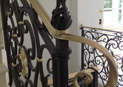 Partenza della scala in ferro battutto con foglie e riccioli fatti a mano con fascette e legacci dorati e corrimano in ottone collocata in villa privata in Costa Azzurra
