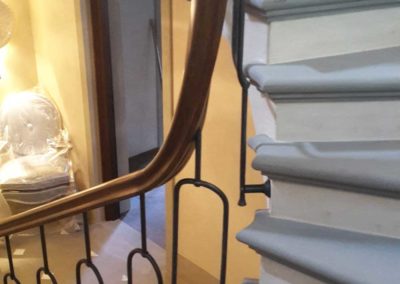 Scala in ferro battutto con elementi verticali forgiati a mano e corrimano in pregiato legno curvato collocata in villa privata in Costa Azzurra