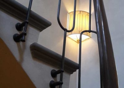 Partenza della scala in ferro battutto con elementi verticali forgiati a mano e corrimano in pregiato legno curvato collocata in villa privata in Costa Azzurra