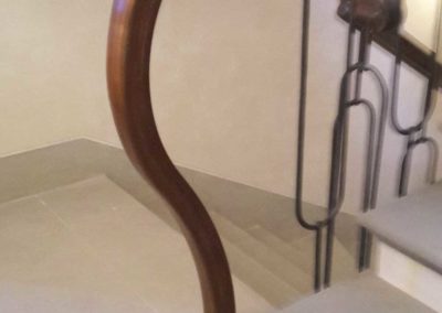 Partenza della scala in ferro battutto con elementi verticali forgiati a mano e corrimano in pregiato legno curvato collocata in villa privata in Costa Azzurra