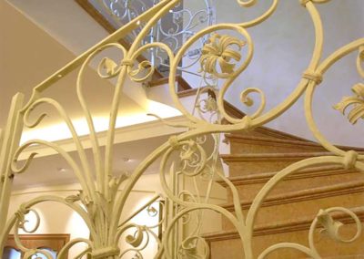 Scala in ferro battutto color pastello con fiori e riccioli fatti a mano e corrimano in ottone collocata in villa privata a Mosca